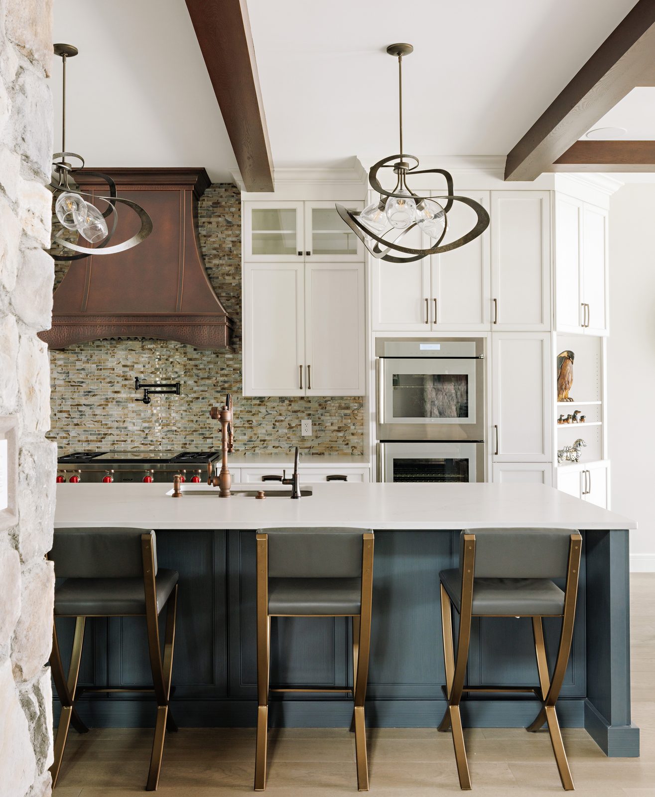 Kitchen island millwork with copper hood and stone wall